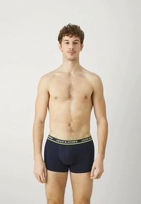 Boxeri scurți de culoare albastră închisă, cu un brâu cu logo galben, fabricați din bumbac, având un design ajustat și o textură netedă.