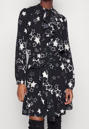Robe noire avec un motif d'étoiles blanches, décolleté froncé, manches longues avec poignets, et une ceinture à nouer à la taille, tissu texturé.