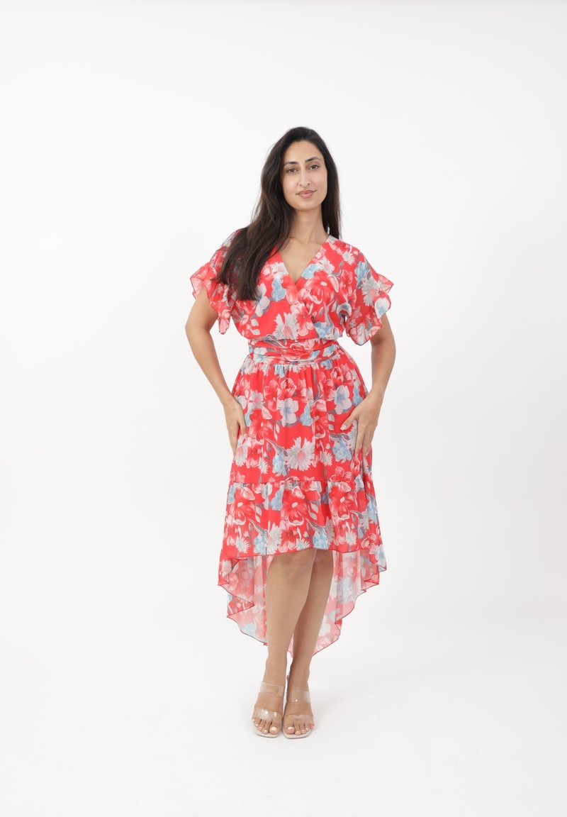 Robe florale rouge avec des manches courtes à volants, un design croisé et une finition asymétrique. Comprend des fleurs bleues et une taille cintrée. Sandales transparentes à talons.