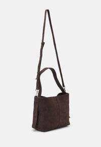 Borsa a spalla in suede marrone scuro con tracolla regolabile e manico corto, esposta su uno sfondo bianco.