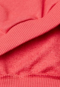 Coral knit fabric with ribbed texture and smooth finish. Features layered design with contrasting stitching along the edges.