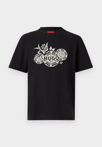 Μαύρο κοντομάνικο T-shirt με λευκό λουλουδένιο σχέδιο και πουλί που περιβάλλει τη λέξη «HUGO» στο κέντρο του στήθους.