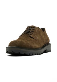 Chaussures en suède marron à lacets avec un bout arrondi et une épaisse semelle en caoutchouc noir présentant un motif de relief.