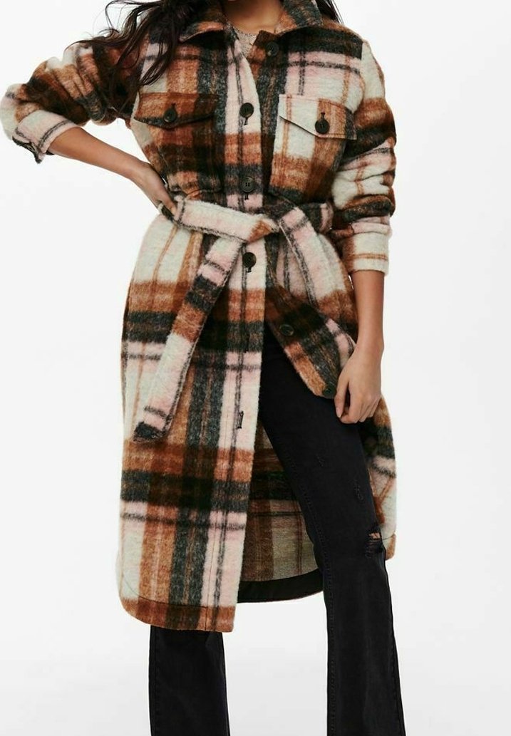 Manteau en polaire à carreaux dans les tons marron, crème et vert. Il présente une fermeture à boutons sur le devant, deux poches poitrine et une ceinture à la taille. Manches longues.