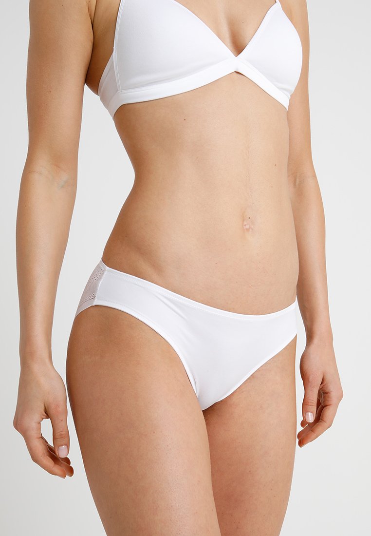 Witte bikini onderkant van gladde stof, met subtiele mesh details aan de zijkant. Naadloos ontwerp met een lage taille.