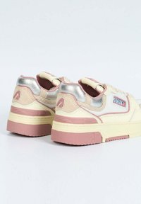 Sneakers a bassa altezza color crema con dettagli rosa, dotate di un tacco metallico argento, suola in gomma testurizzata e patch con logo sul lato.