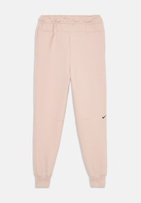 Ljust rosa Nike sweatpants med elastisk midja, sidofickor, ribbade muddar och liten svart Nike-logotyp på höger ben.