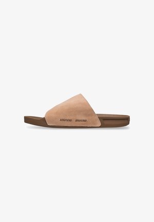 Suede slide sandal in beige with a triangular upper, brown rubber sole, and decorative zigzag stitching on the side. Smooth texture.