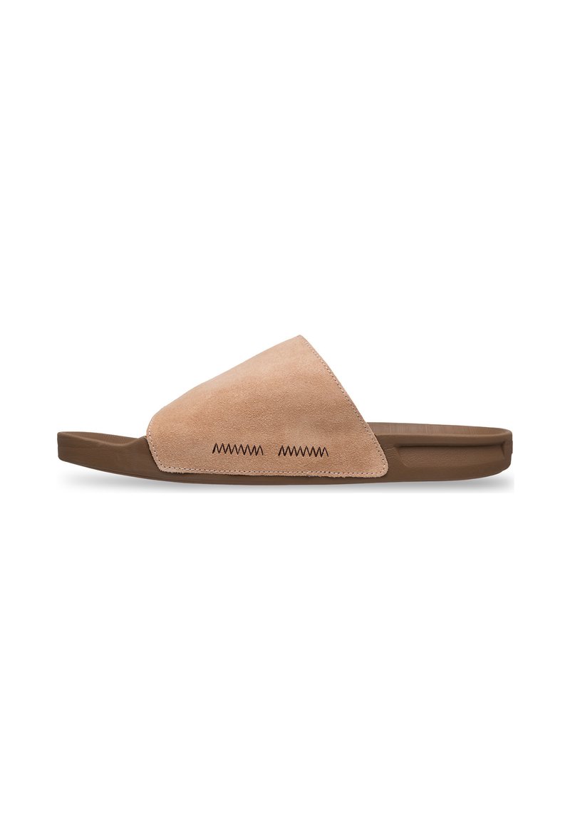 Suède badslipper in beige met een driehoekige bovenkant, bruine rubberen zool en decoratieve zigzagstiksels aan de zijkant. Soepele textuur.