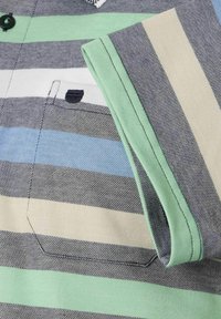 Polo w paski w kolorze szarym, niebieskim, zielonym i beżowym. Posiada kieszeń, kołnierzyk oraz kontrastowe zielone wykończenia mankietów. Miękka tekstura materiału.