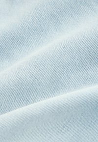 Lysblåt denimstof med en glat tekstur og et fint, diagonalt vævemønster, der viser subtile variationer i farve og dybde.