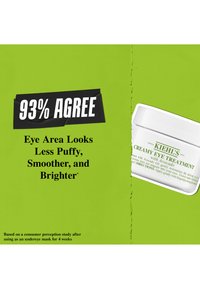 Die Kiehl's Creamy Eye Treatment-Dose in Weiß mit glatter Oberfläche zeigt grünen Text auf einem gespaltenen Hintergrund, der im Kontrast zu einer leuchtend grünen Farbe steht.