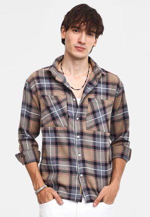 Camisa de cuadros en marrón, gris y marino con dos bolsillos en el pecho, diseño de botones, mangas remangadas y detalles de costura en contraste.