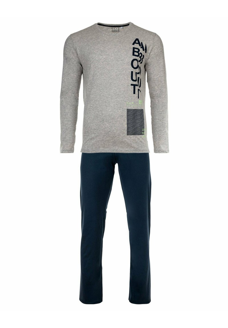 Grijze langemouwen T-shirt met tekst en designelementen; gecombineerd met marineblauwe broek. De stof lijkt zacht en casual.