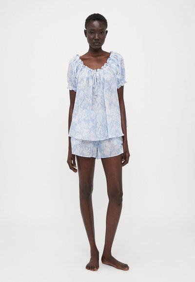 Blue floral-patterned pajama set featuring a short-sleeve top with a ruffled neckline and matching shorts, both in lightweight fabric.