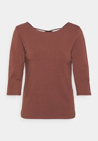 Brun, topp med trekvartslånga ärmar gjord av mjukt tyg. Har en bred, rund halsringning med ett korskedje detaljer på baksidan.