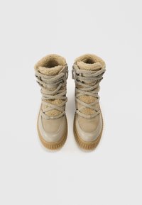 Bottes beiges avec doublure en fausse fourrure, suède texturé et semelles en caoutchouc. Comprennent des lacets et une fermeture éclair latérale pour un enfilage facile.