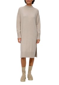 Abito lavorato a maglia beige con colletto alto, maniche lunghe, polsini a coste, spacco laterale e silhouette dritta, abbinato a stivali alla caviglia color taupe.