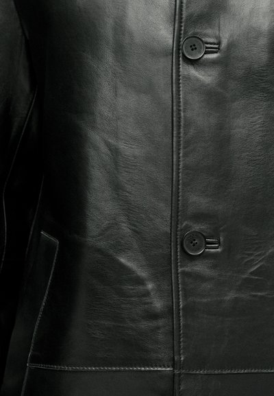 Schwarze Lederjacke mit glatter Textur, zwei Knöpfen und einer einzelnen Seitentasche mit sichtbaren Nähten.