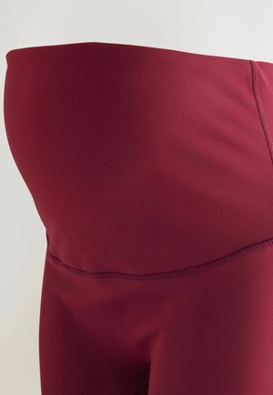 Legginsy ciążowe w burgundowym kolorze z elastycznego materiału. Posiadają wysoki stan, gładką fakturę oraz płaskie szwy dla komfortu i wsparcia.