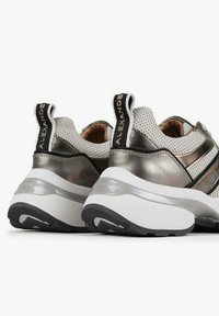 Sneakers argento e nere con tomaia in mesh, colletto imbottito e suola bianca a contrasto. Dettagli includono strisce orizzontali e marchio sul tallone.