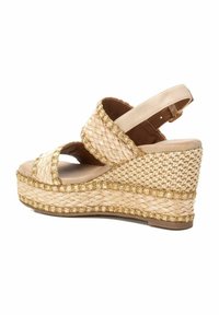 Sandalo con zeppa in materiale beige intrecciato, con cinturini incrociati e una cinghia sul retro alla caviglia. Accentato da cuciture dorate lungo la suola.