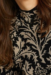 Maglione nero con motivo floreale metallico dorato, design a collo alto e tessuto testurizzato. Mostra dettagli intricati e forme fluide.