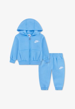 Svetlo modra Nike otroška trenirka z zadrgo in kapuco ter hlačami z elastičnim pasom, obe z logotipnimi poudarki.