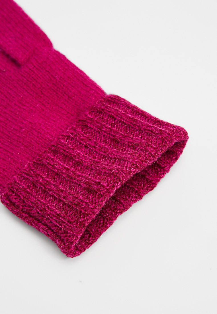 Jasnoróżowy, dziany mankiet o prążkowanej strukturze, złożony na gładkim jasnym tle.
