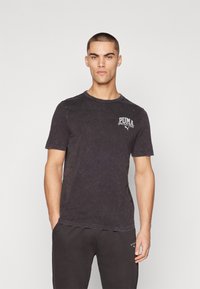 Black, short-sleeve t-shirt with a round neck, textured fabric, and a white Puma logo on the upper left chest area. Casual fit.