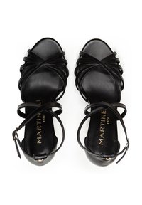 Sandalias de tacón alto de cuero negro con tiras entrelazadas, diseño de punta abierta y correa en el tobillo. Branding dorado en la plantilla.