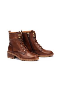 Bottes chevilles en cuir brun avec œillets et lacets dorés, fermeture éclair sur le côté, accents texturés et talon empilé. Semelle en caoutchouc pour une bonne traction.