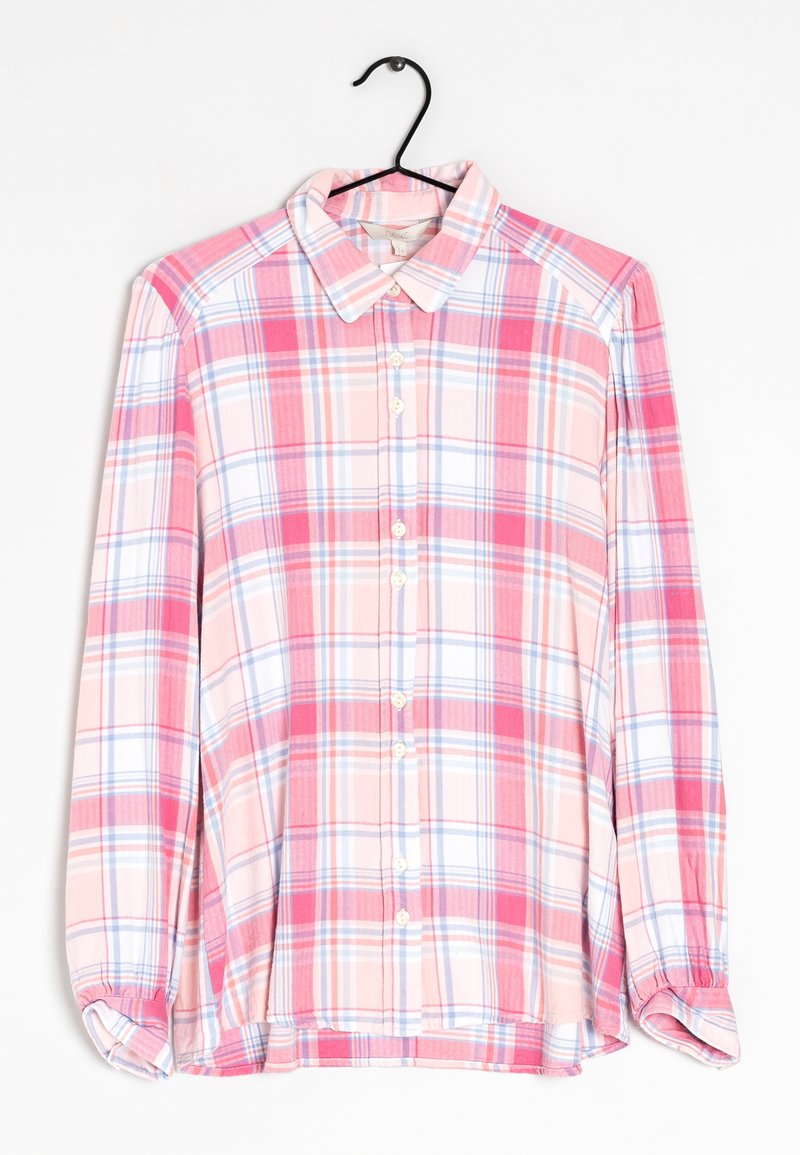 Chemise à manches longues boutonnée avec un motif à carreaux rose, blanc et bleu, suspendue sur un cintre noir sur fond blanc.