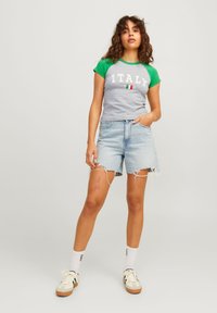 Pelēka un zaļa t-kreklu ar tekstu "ITALY" un karogu, apvienots ar gaiši zilām džinsiem ar saplēstiem malām. Ikdienišķa apavi un baltās zeķes.
