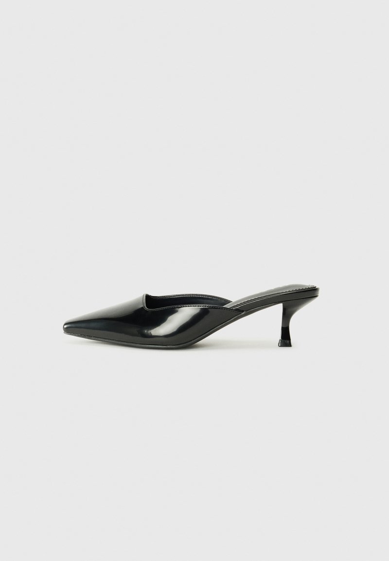 Sorte patenterte skinnmules med spiss tå, lav kitten-hels og buede sider, med en blank overflate og minimalistisk design.