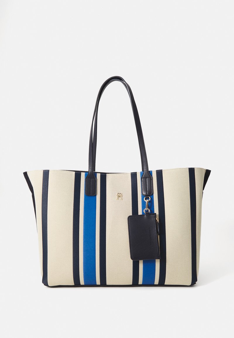 Bolsa de lona con rayas en azul marino, azul y crema. Cuenta con asas dobles, un logo dorado y una cartera extraíble en azul marino unida por un herraje.