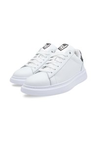 Witte leren sneakers met een gestructureerde afwerking, ronde neus, vlakke witte zool en zwarte accenten op de hiel. Gekleed met veters en met logo op de tong.