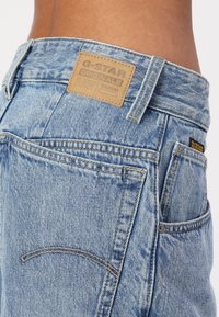 Jeans din denim de culoare bleu deschis, cu o etichetă din piele G-Star la brâu, cusături contrastante și un design standard cu cinci buzunare.