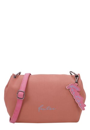 Sac à main couleur pêche avec une finition en tissu lisse, une bandoulière rose et un accent en métal argenté. Il présente un porte-clés logo rose ludique.