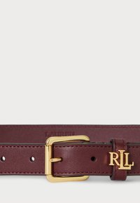 Bordový kožený opasok so zlatou kovovou sponou, obsahujúci vyvrtané otvory a pútko s logom "RL". Hladký povrch a klasický dizajn.