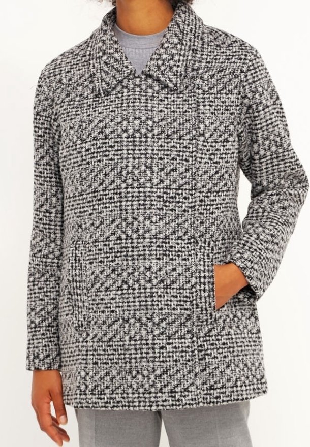 Šedý a černý kostkovaný kabát s velkým límcem, dvěma předními kapsami a texturovanou látkou. Design se vyznačuje volně střiženou siluetou.