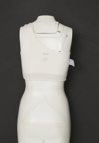 Biely asymetrický športový podprsenka s jedným širokým ramienkom na mannequinne na tmavosivom pozadí