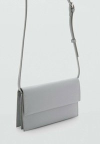 Borsa a tracolla in pelle grigia con chiusura a patta, forma rettangolare, design minimalista e tracolla regolabile per un utilizzo versatile.