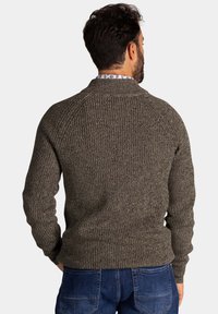 Donkergrijze gebreide trui met een gestructureerde afwerking, geribbelde manchetten en een ronde hals, van de achterkant getoond. Draagend over donkerblauwe jeans.