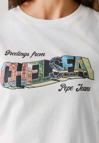 White cotton t-shirt featuring "Greetings from CHELSEA" graphic with colorful cityscape images and "Pepe Jeans" text in a playful font.