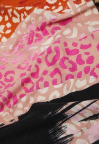 Tissu multicolore présentant un mélange d'imprimés animaliers rose, orange et noir. Texture douce avec des motifs variés sur toute la surface.