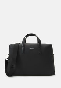Borsa da viaggio nera con finitura liscia e opaca, doppio manico superiore e tracolla removibile. Presenta un logo del marchio discreto sulla parte anteriore.