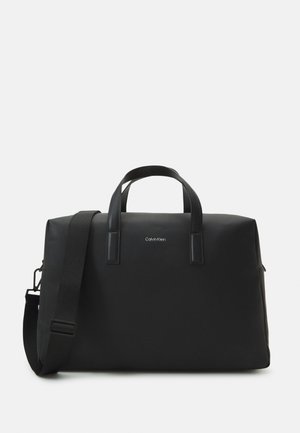 Borsa da viaggio nera con finitura liscia e opaca, doppio manico superiore e tracolla removibile. Presenta un logo del marchio discreto sulla parte anteriore.