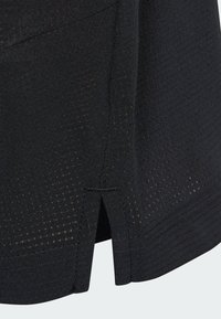 Black athletic skirt with a textured design, featuring small perforations, a slight slit at the hem, and a clean stitched finish.