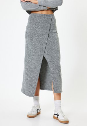 Gonna midi grigia a coste con design a portafoglio e spacchi laterali, abbinata a sneakers bianche e calze alla caviglia. Tessuto morbido e testurizzato.